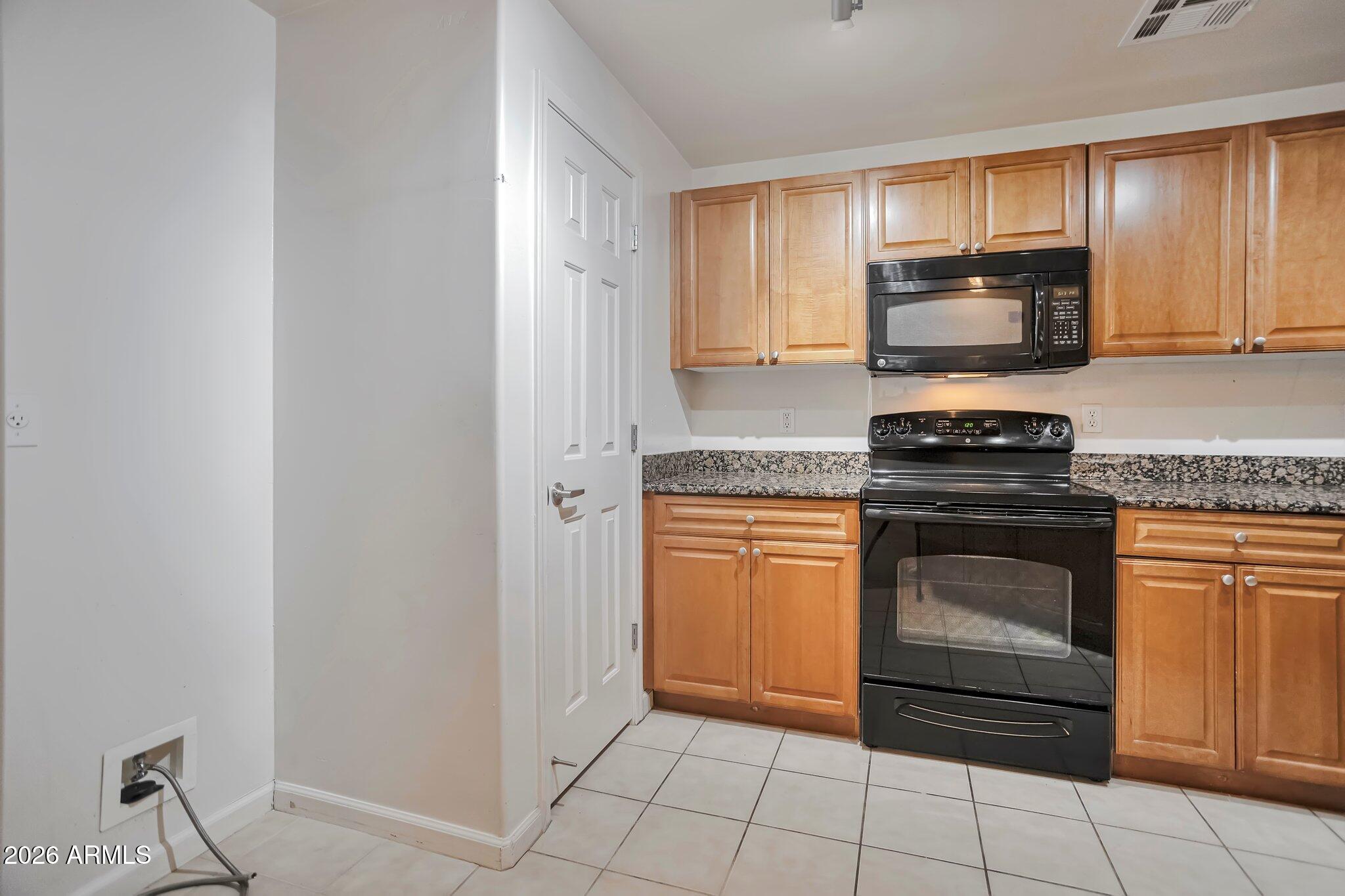 1920 East Bell Road, Unit 1006 Phoenix, AZ 85022 - Photo 11 of 25 a kitchen with granite countertop a stove top oven microwave and cabinets