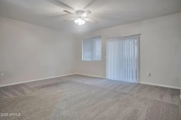 an empty room with a chandelier fan and windows