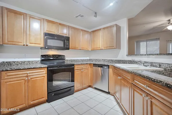 a kitchen with granite countertop a sink cabinets and stainless steel appliances