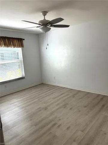an empty room with a window and a ceiling fan