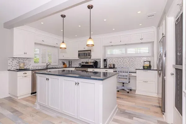 a kitchen with stainless steel appliances granite countertop a sink a stove a refrigerator and island with wooden floor