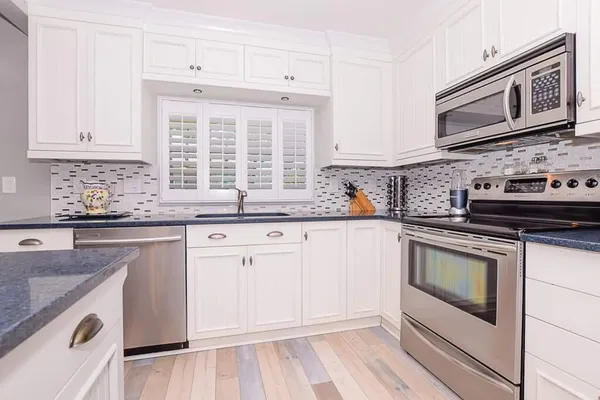 a kitchen with granite countertop white cabinets and white appliances