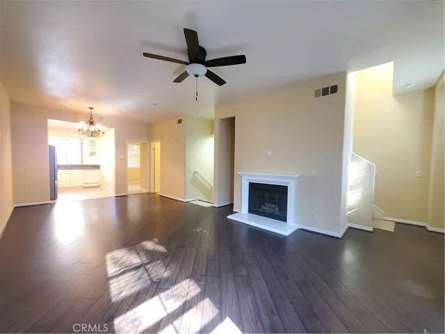 a view of a livingroom with wooden floor a ceiling fan and a kitchen