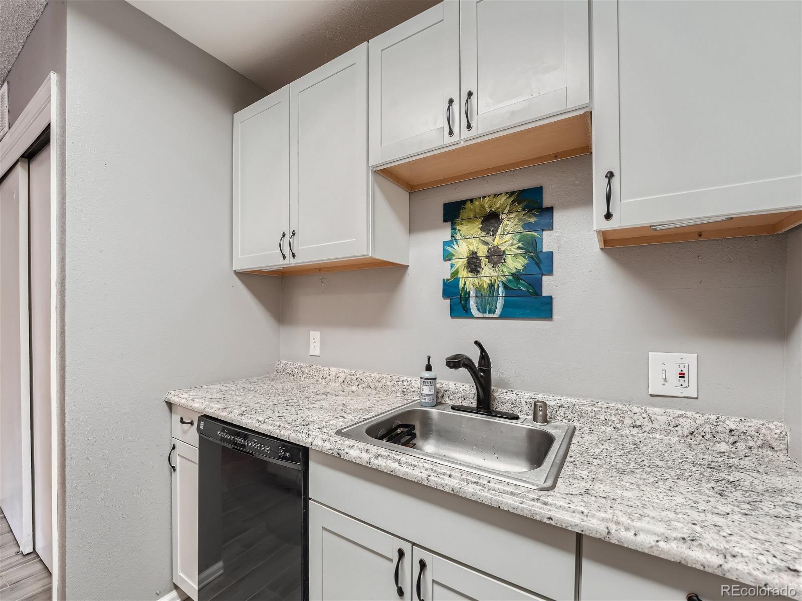 4911 Garrison Street, Unit 202G Wheat Ridge, CO 80033 - Photo 11 of 33 a kitchen with stainless steel appliances granite countertop a sink dishwasher and cabinets with wooden floor