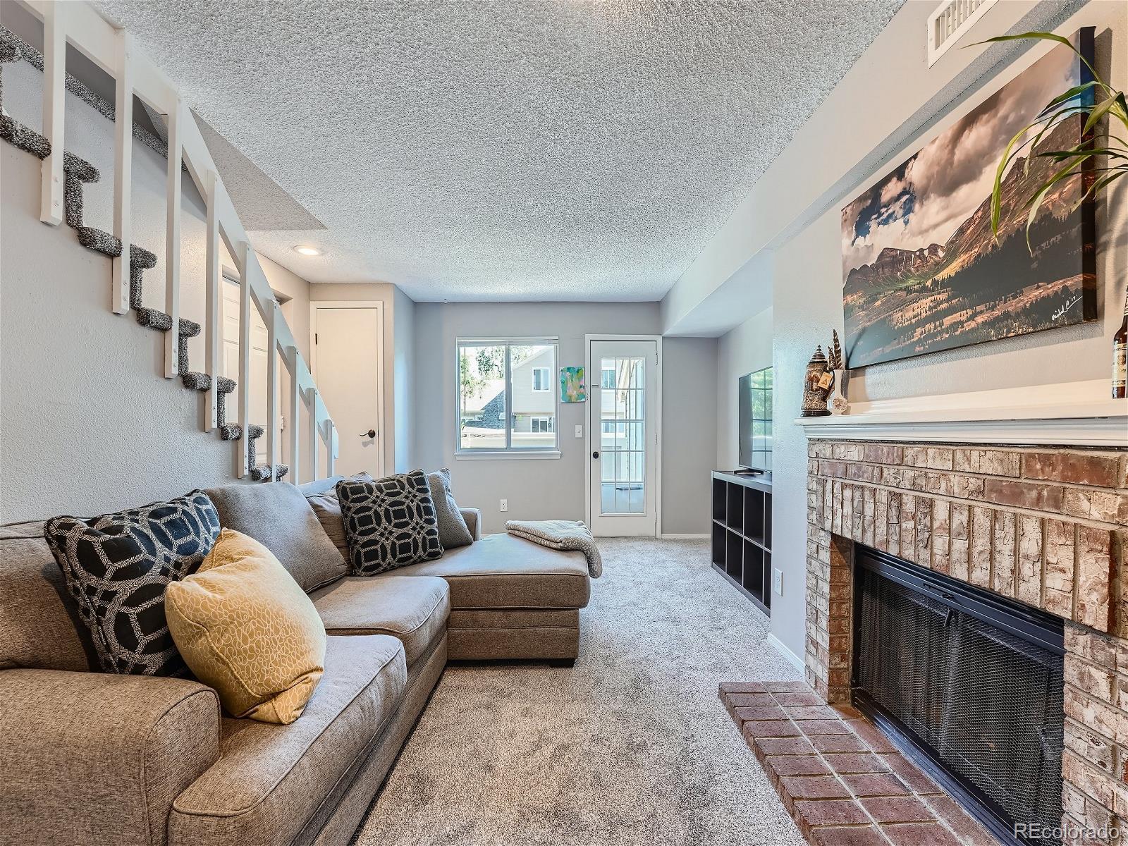 4911 Garrison Street, Unit 202G Wheat Ridge, CO 80033 - Photo 7 of 33 a living room with furniture a fireplace and a floor to ceiling window