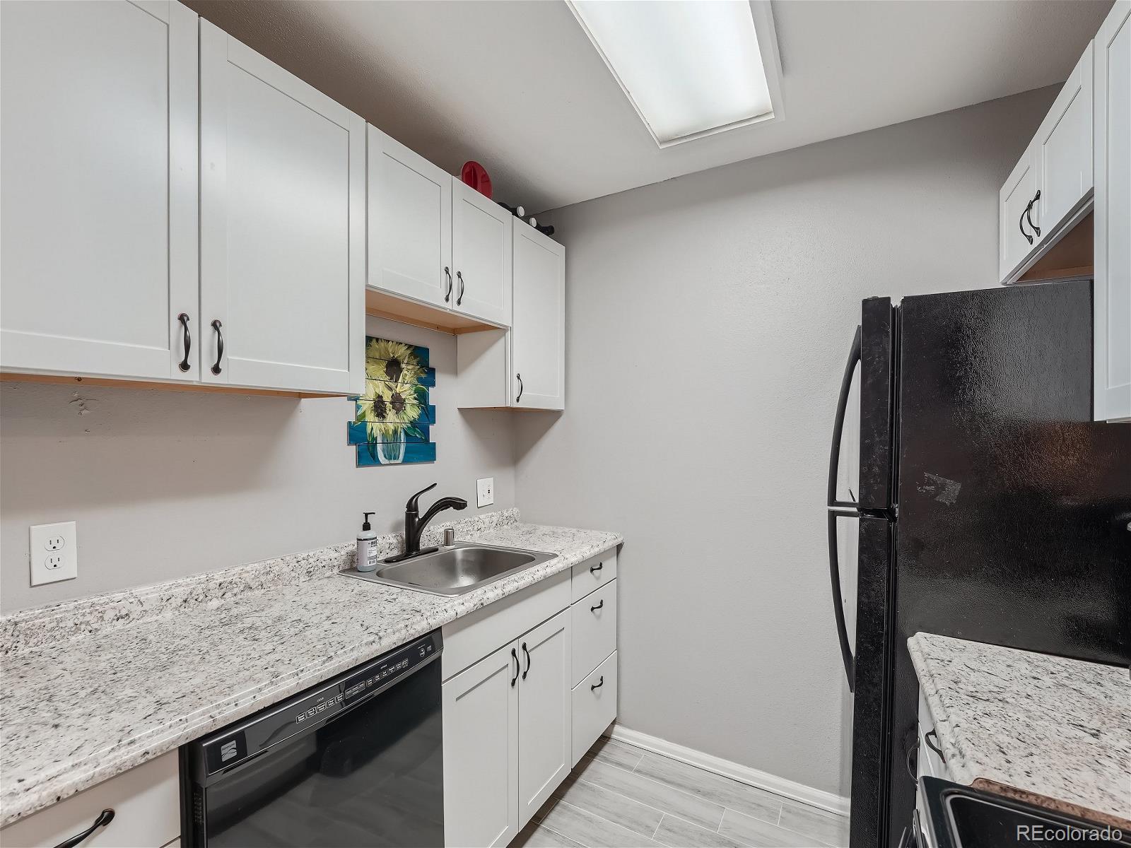 4911 Garrison Street, Unit 202G Wheat Ridge, CO 80033 - Photo 8 of 33 a kitchen with stainless steel appliances granite countertop a sink refrigerator and microwave