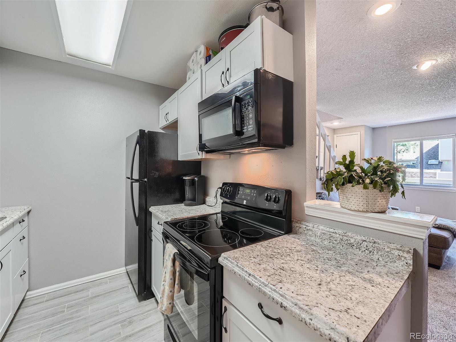 4911 Garrison Street, Unit 202G Wheat Ridge, CO 80033 - Photo 9 of 33 a kitchen with stainless steel appliances granite countertop a stove top oven a sink and a microwave