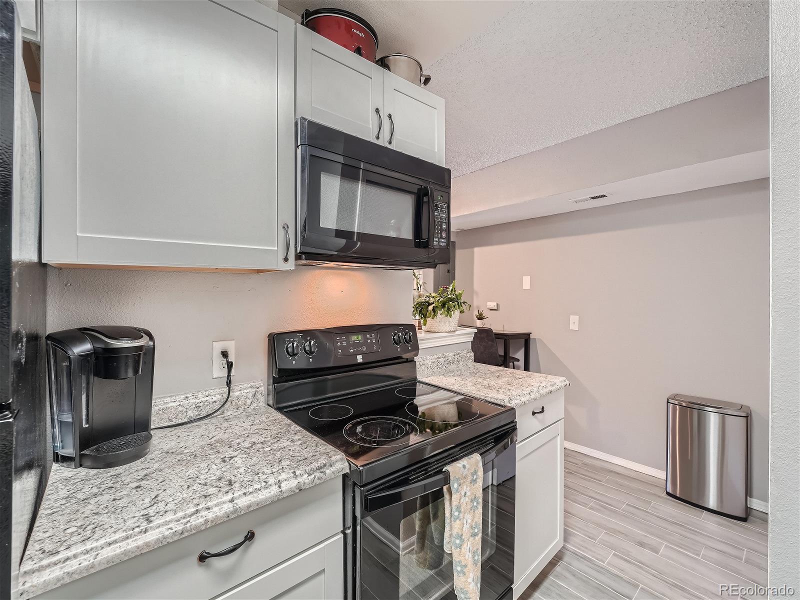 4911 Garrison Street, Unit 202G Wheat Ridge, CO 80033 - Photo 10 of 33 a kitchen with granite countertop a stove sink and microwave