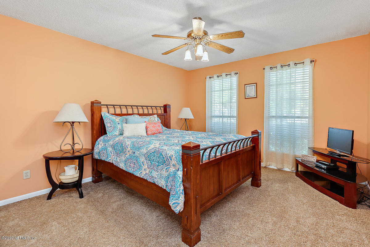 12819 Beaubien Road Jacksonville, FL 32258 - Photo 9 of 17 a bedroom with a bed and a chandelier