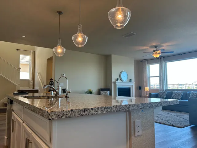 a kitchen with granite countertop a stove a sink and a living room view