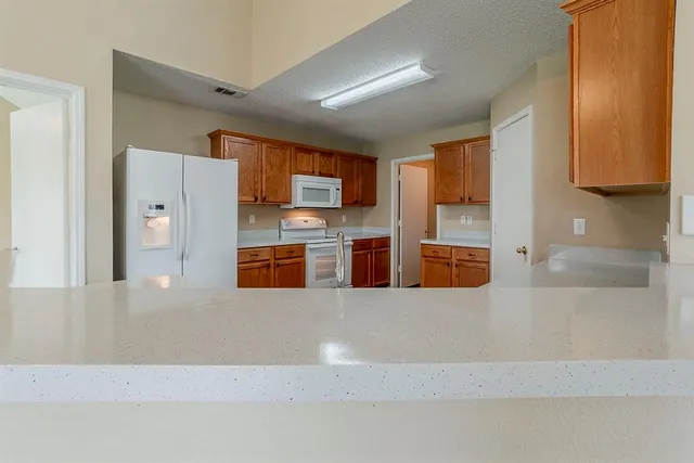 a large kitchen with stainless steel appliances a large counter top a stove and a refrigerator