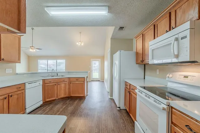 a kitchen with granite countertop cabinets stainless steel appliances a sink and wooden floor