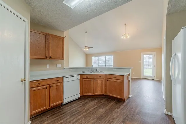 a kitchen with stainless steel appliances granite countertop wooden floors and white cabinets