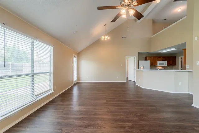 a view of an empty room with window and wooden floor