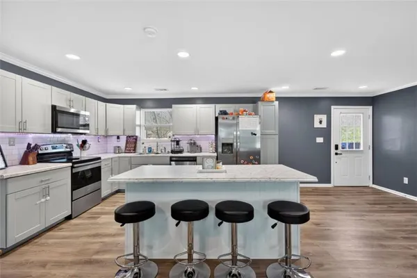 a kitchen with a stove a refrigerator and a dining table with wooden floor