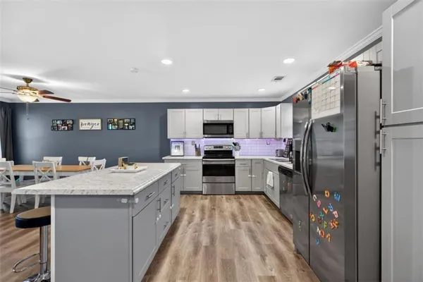 a large kitchen with a large counter top stainless steel appliances and cabinets