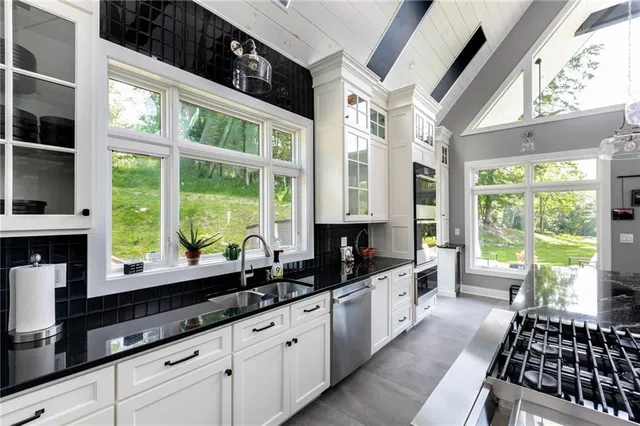 a large kitchen with granite countertop a large window and white stainless steel appliances
