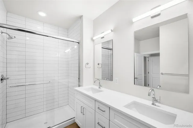 a bathroom with a double vanity sink mirror and shower