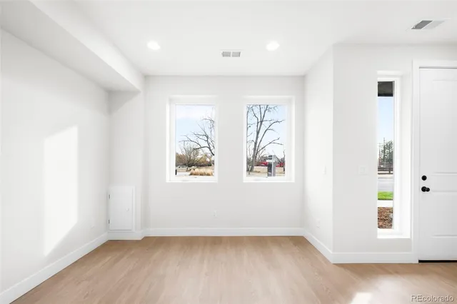an empty room with wooden floor and windows