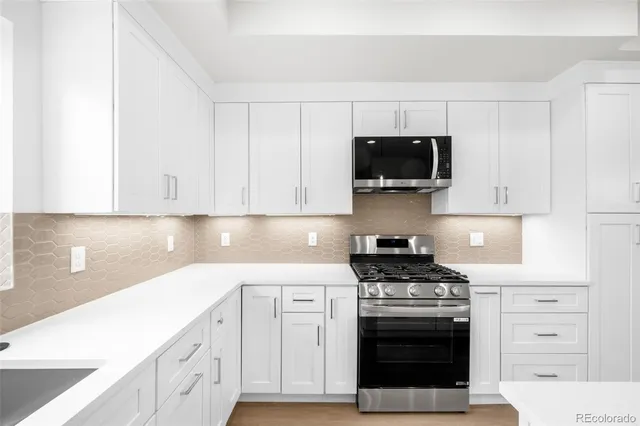 a kitchen with white cabinets and stainless steel appliances