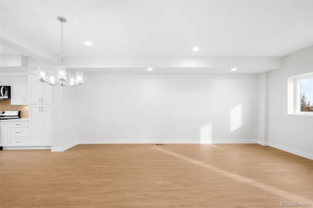 a view of empty room with wooden floor and chandelier