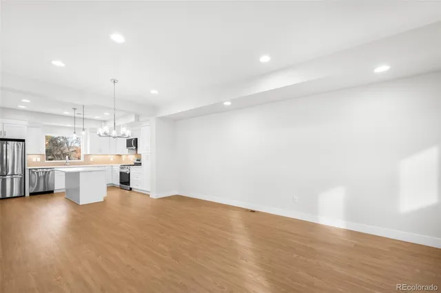 a open kitchen with a sink dishwasher a dining table and chairs with wooden floor