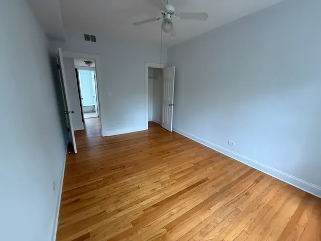 a view of empty room with wooden floor and fan