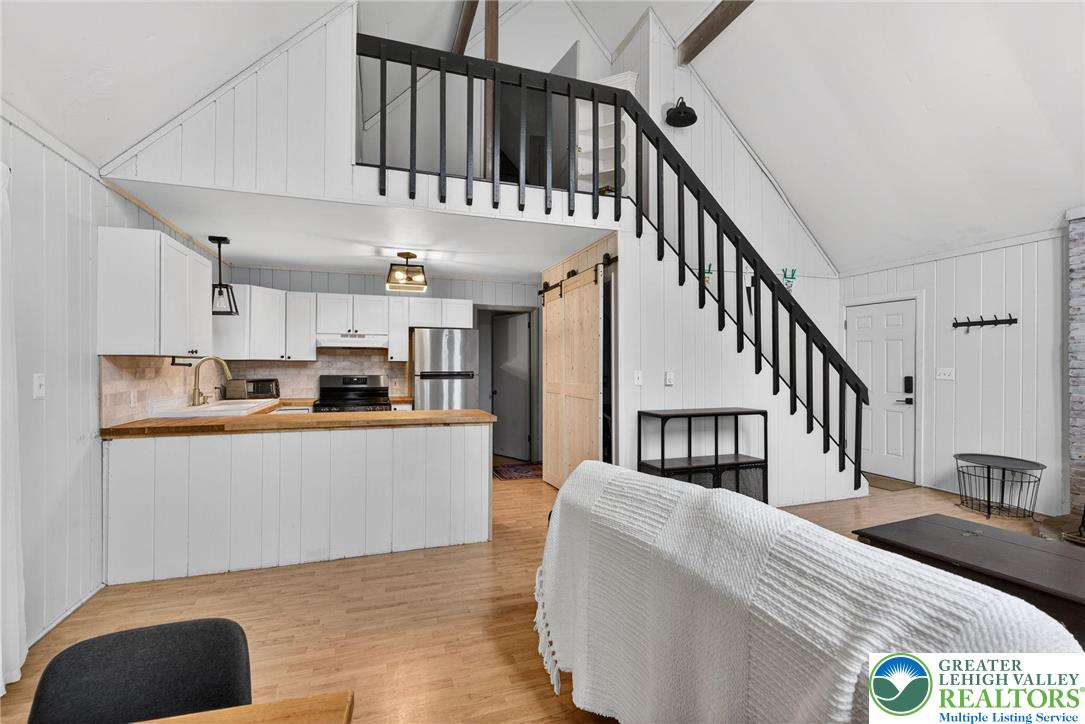 149 Regent Street Bushkill, PA 18324 - Photo 14 of 32 a living room with stainless steel appliances kitchen island granite countertop a refrigerator a stove a dining table and chairs with wooden floor