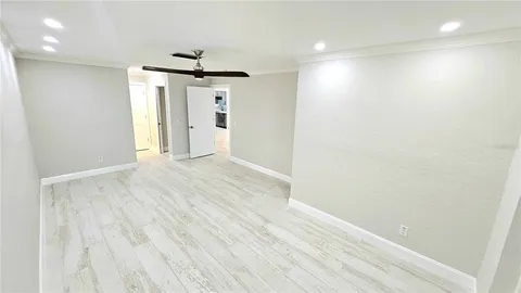 an empty room with wooden floor and ceiling fan