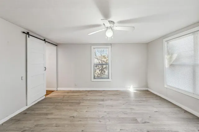 a view of an empty room with wooden floor and window