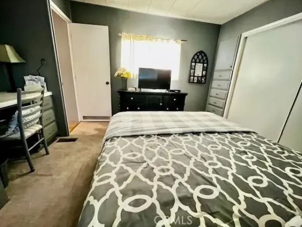 a bedroom with a bed and a flat tv screen on dresser