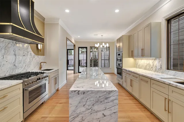a large white kitchen with stainless steel appliances granite countertop a stove and a sink