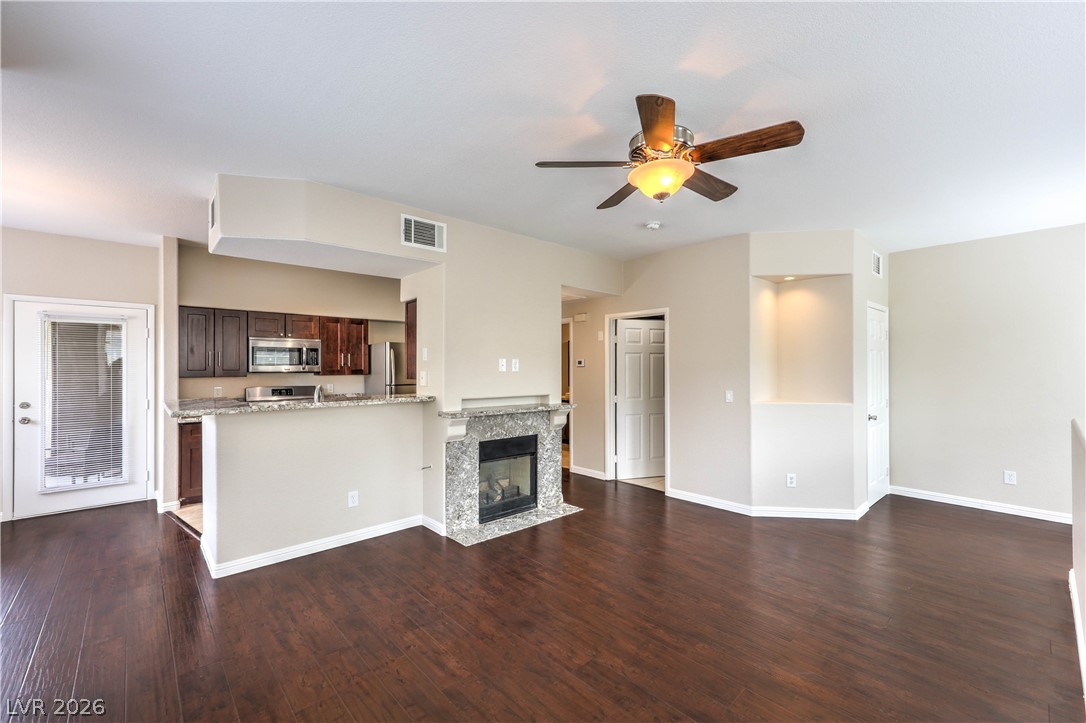 9050 West Warm Springs Road, Unit 2033 Las Vegas, NV 89148 - Photo 5 of 30 Hardwood floors and a cozy fireplace create a welcoming open-concept living area.