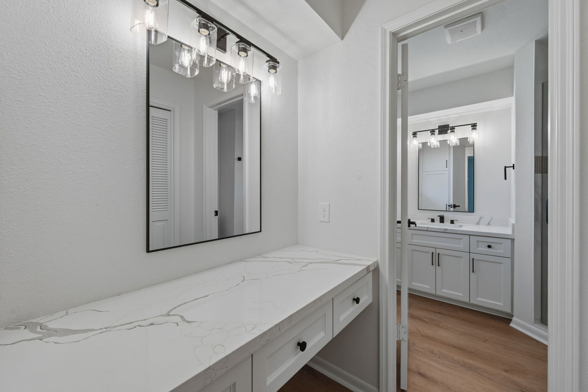 210 Ridgemont Drive Alvin, TX 77511 - Photo 22 of 27 This photo showcases a modern bathroom with a sleek marble countertop and contemporary lighting fixtures. The space features a large mirror and a dual-sink vanity, offering functionality and style.