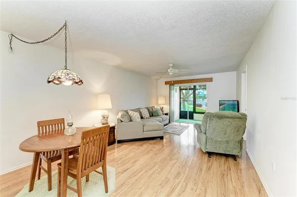 a living room with couches chandelier and kitchen view