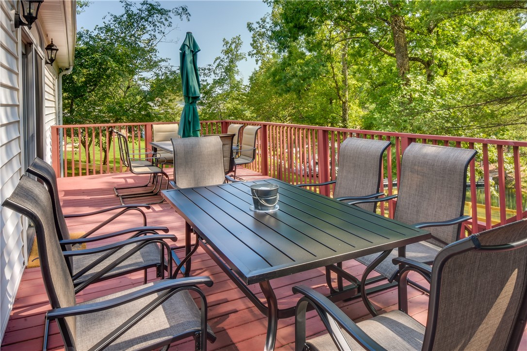206 Petty Road Seneca, SC 29672 - Photo 38 of 48 A spacious wooden deck with a dining set provides an inviting outdoor entertaining area, overlooking abundant greenery.