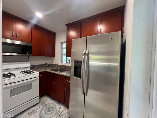 a kitchen with granite countertop a refrigerator stove and cabinets