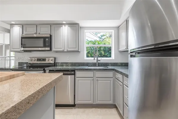 a kitchen with stainless steel appliances granite countertop a stove a sink and a microwave