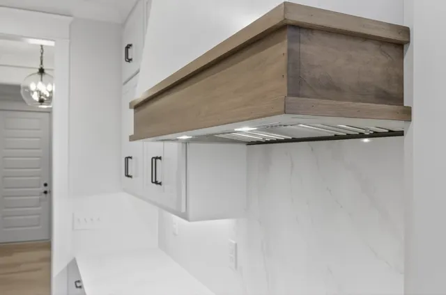 a view of a room with a chandelier fan and wooden floor