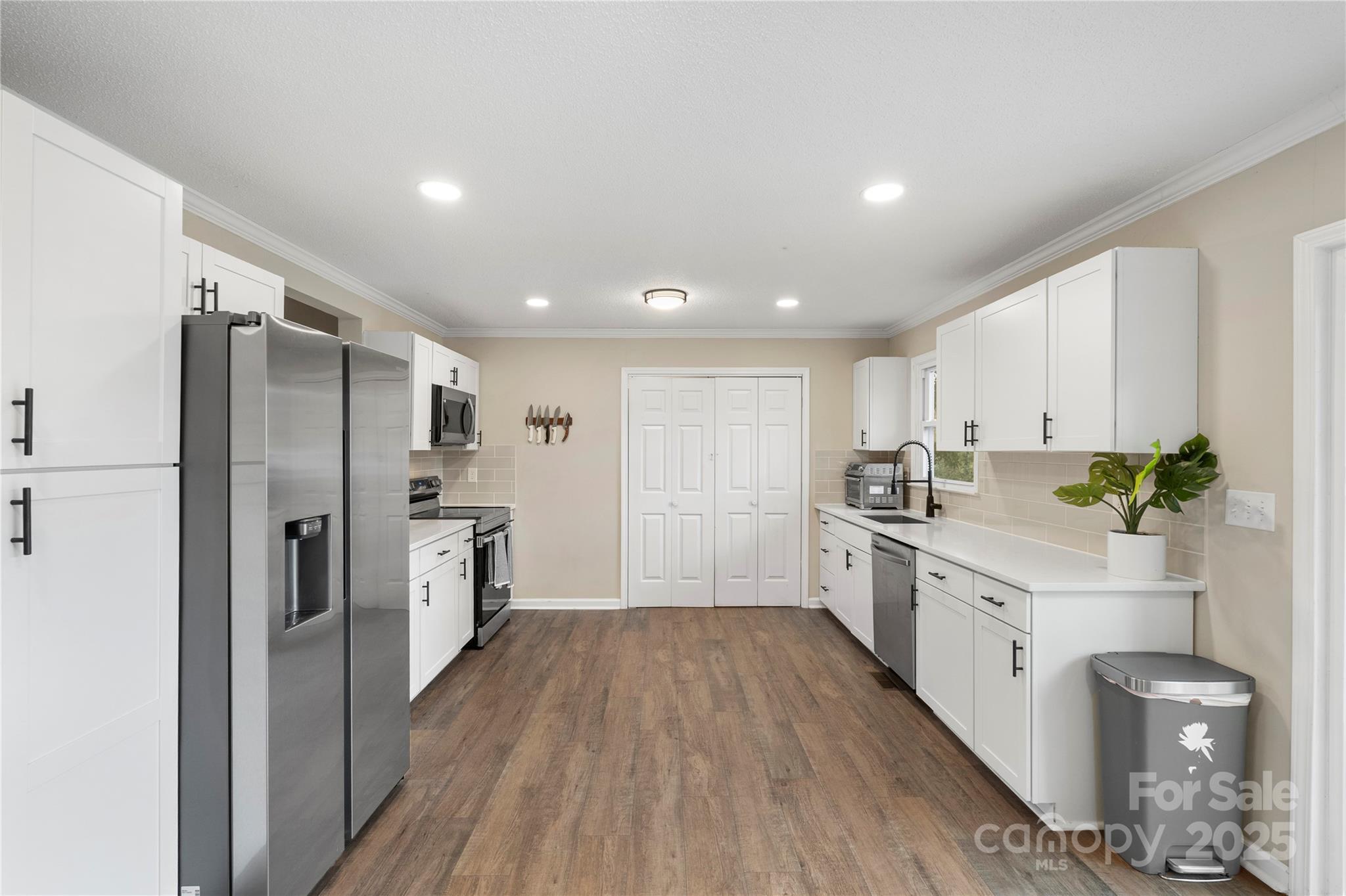 2302 Old Hickory Grove Road Mount Holly, NC 28120 - Photo 20 of 48 a large kitchen with a refrigerator a sink dishwasher a stove and white cabinets with wooden floor