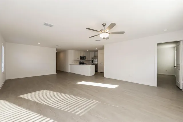 a view of a livingroom with a kitchen space with wooden floor
