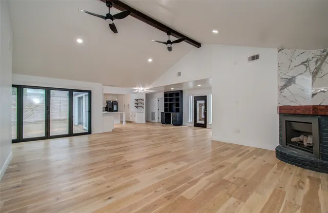 a view of an empty room with wooden floor fireplace and a window