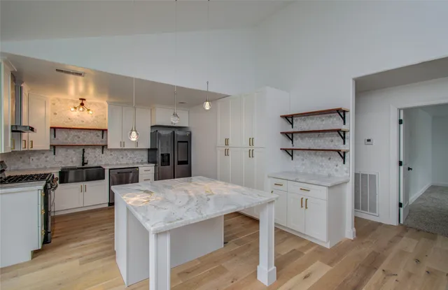 a kitchen with stainless steel appliances kitchen island granite countertop a table chairs in it and wooden floors