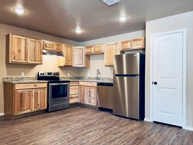 a kitchen with granite countertop stainless steel appliances a refrigerator a sink and cabinets