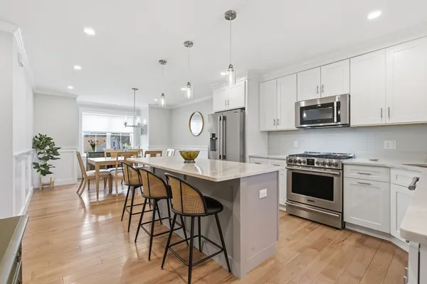 a kitchen with stainless steel appliances a stove a sink a microwave a center island and cabinets