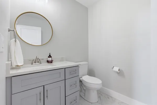 a bathroom with a toilet a sink a mirror and vanity