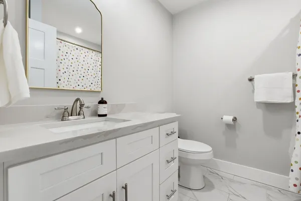 a bathroom with a granite countertop sink a toilet and a mirror