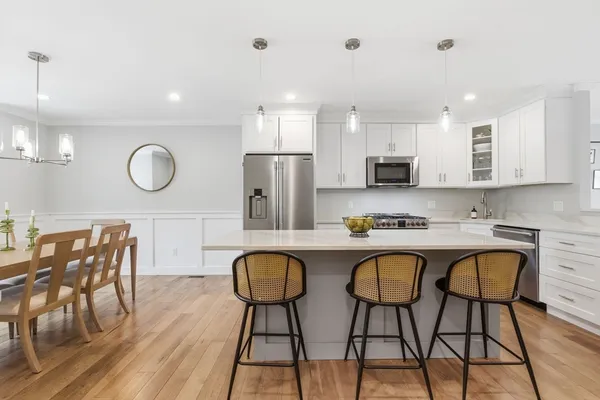 a kitchen with stainless steel appliances granite countertop a dining table chairs stove a sink and a refrigerator