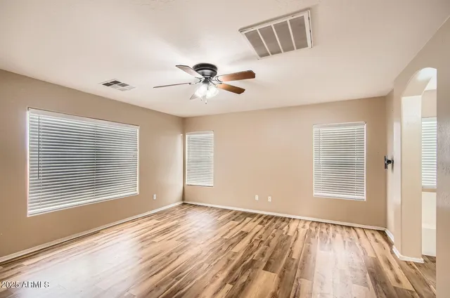 a view of an empty room with a window and wooden floor