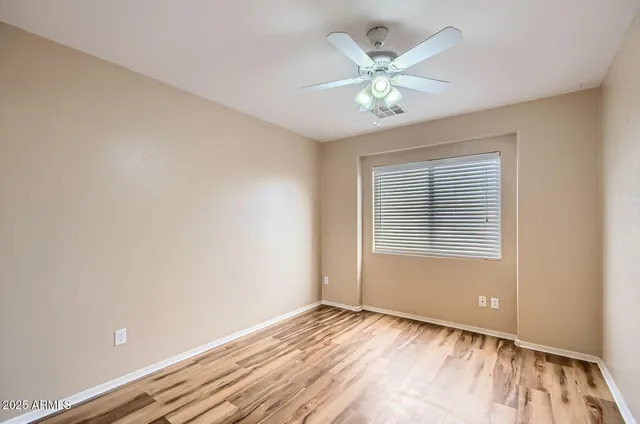 a view of an empty room with chandelier fan and wooden floor